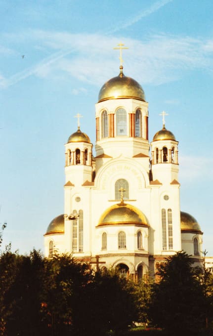 A large white church with gold domes and golden cupola.